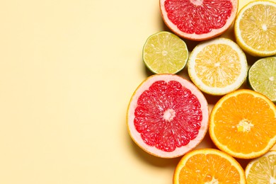 Photo of Different cut citrus fruits on beige table, flat lay. Space for text