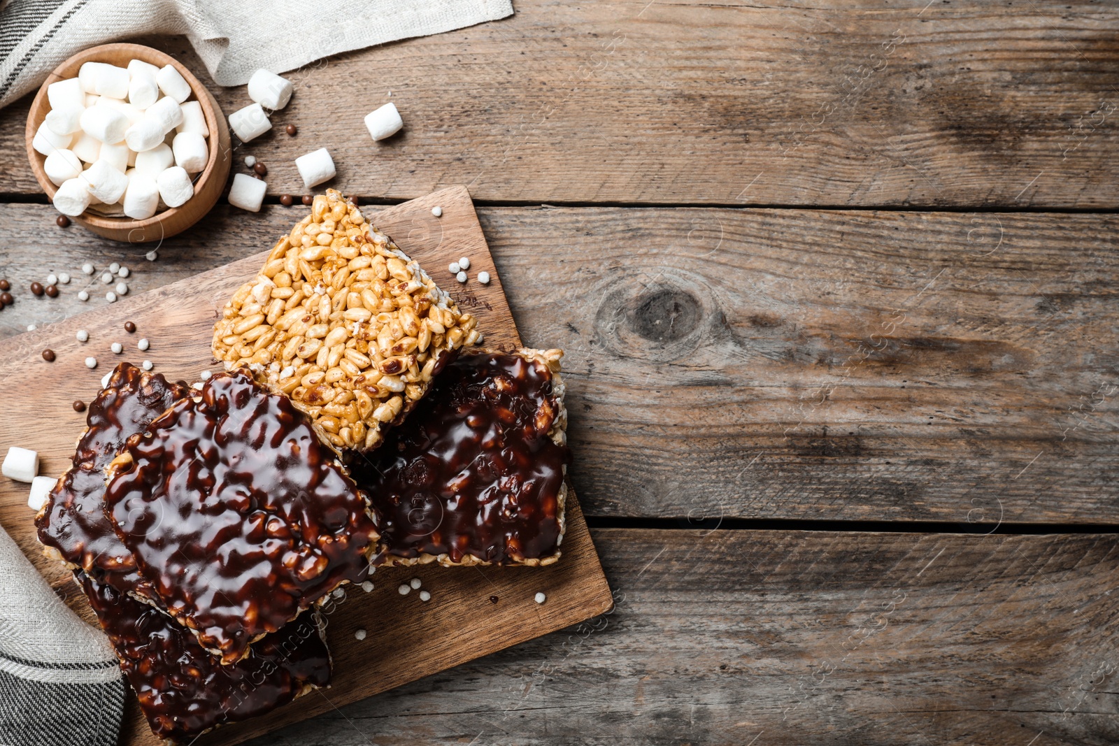 Photo of Delicious rice crispy treats on wooden table, flat lay. Space for text