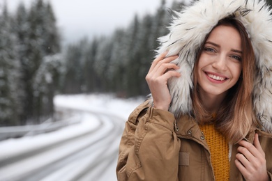 Photo of Young woman in warm clothes outdoors, space for text. Winter vacation