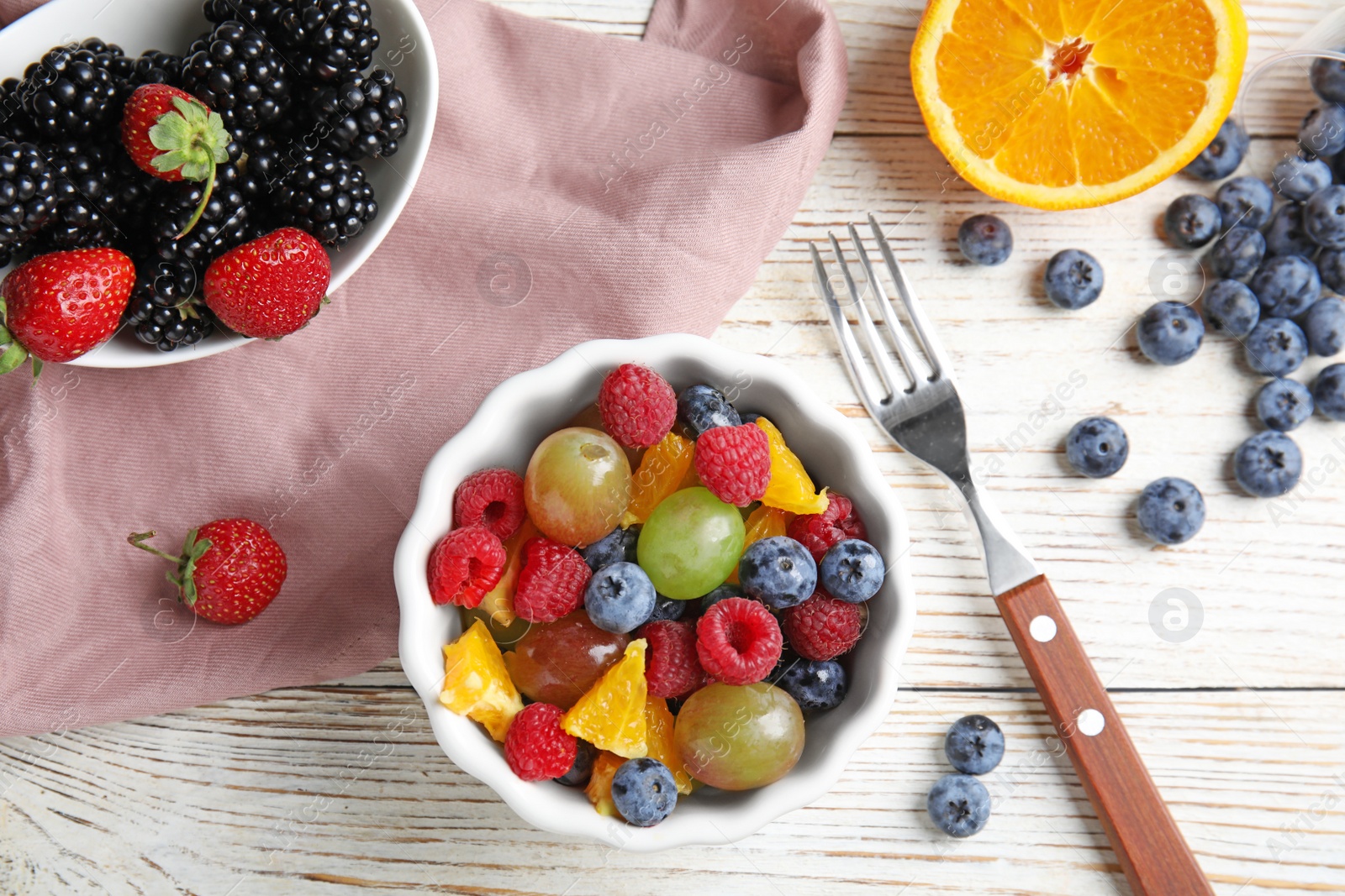 Photo of Fresh tasty fruit salad on white wooden table, flat lay