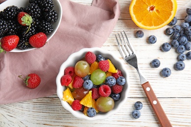 Photo of Fresh tasty fruit salad on white wooden table, flat lay