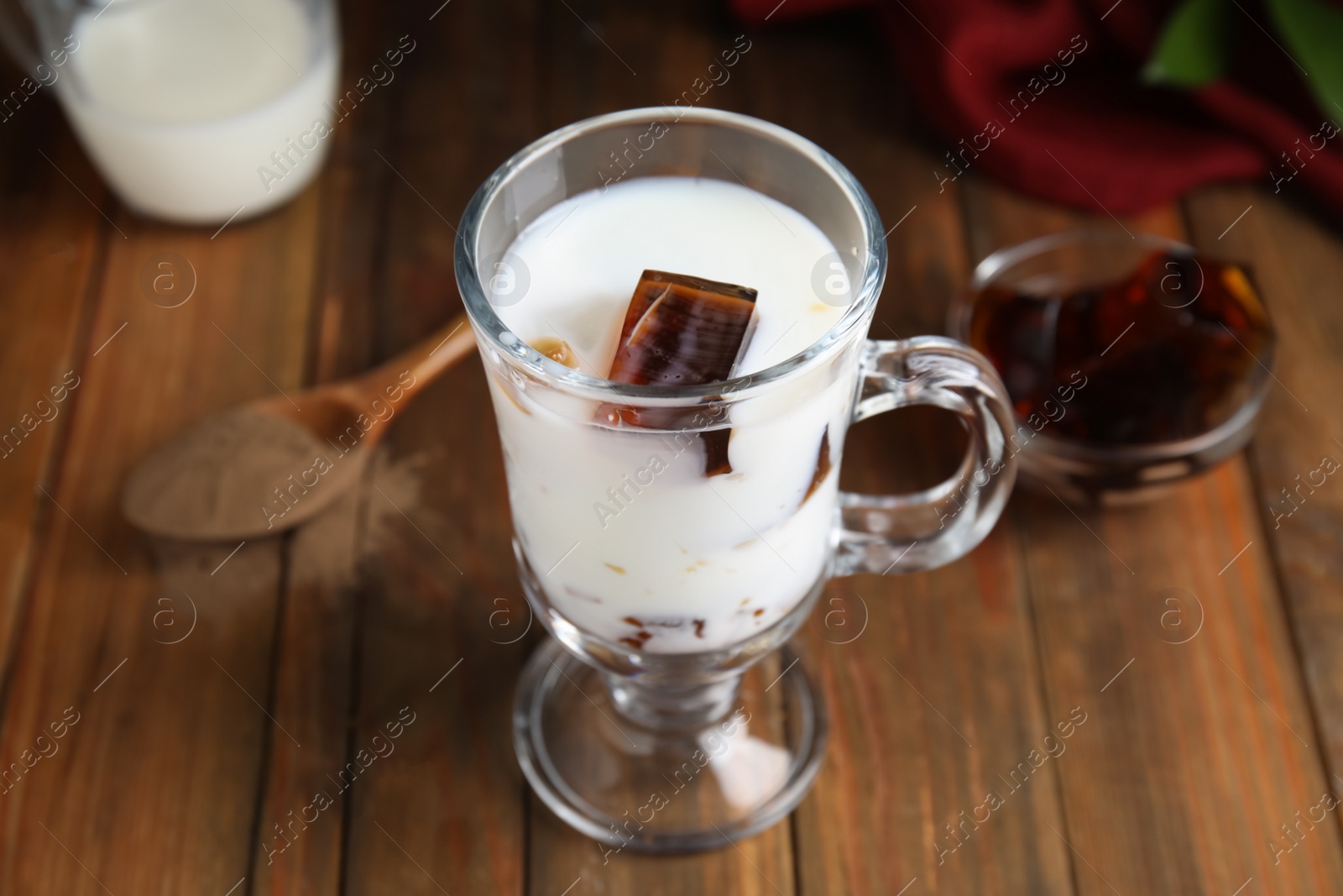 Photo of Glass cup of milk with delicious grass jelly on wooden table, closeup