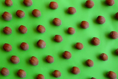 Brown tasty hazelnuts on green background, flat lay