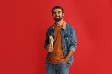 Photo of Happy student with books on red background