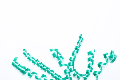 Photo of Turquoise serpentine streamers on white background, top view