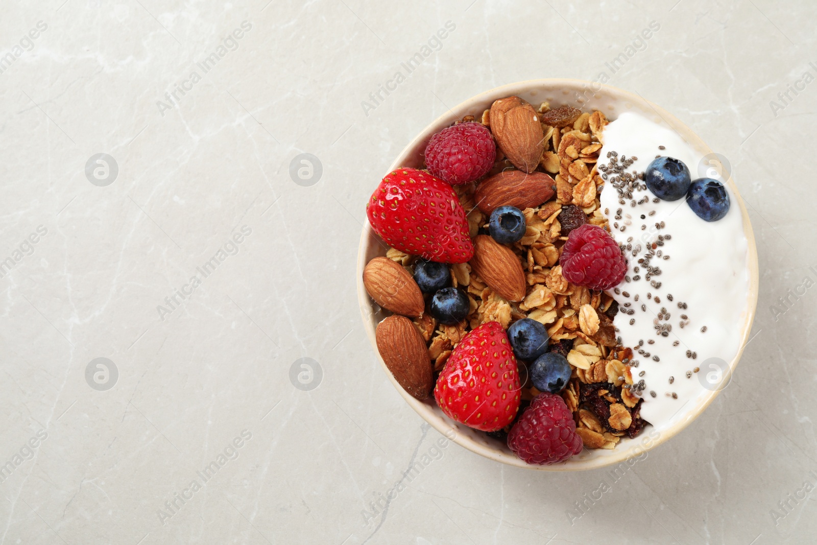 Photo of Tasty homemade granola served on marble table, top view with space for text. Healthy breakfast