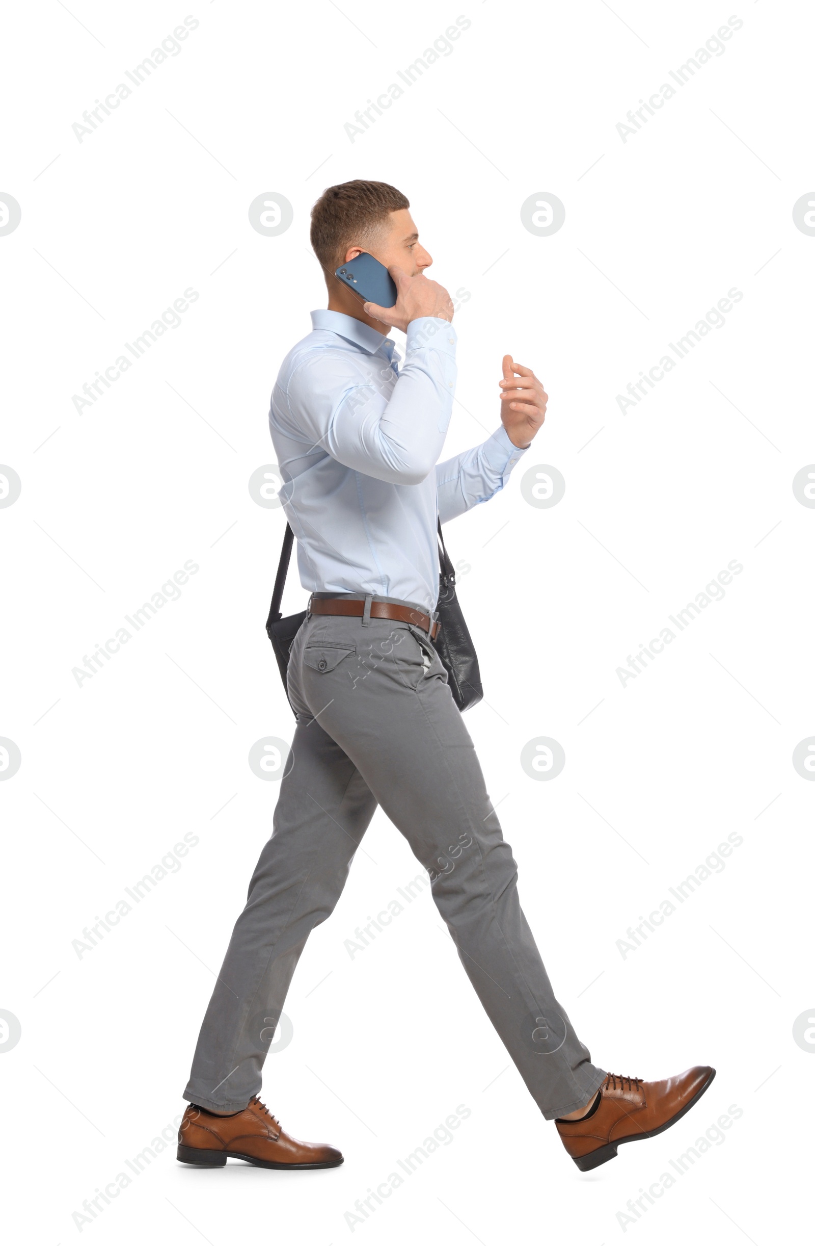 Photo of Man talking on smartphone while walking against white background