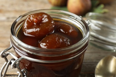 Photo of Jar of tasty sweet fig jam on wooden table, closeup