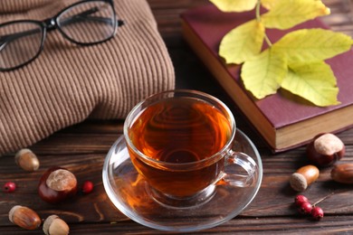 Photo of Cuparomatic tea, book and soft sweater on wooden table indoors, above view. Autumn atmosphere