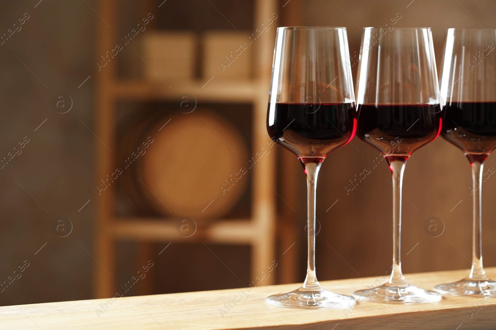 Photo of Glasses of red wine in cellar, space for text. Expensive drink