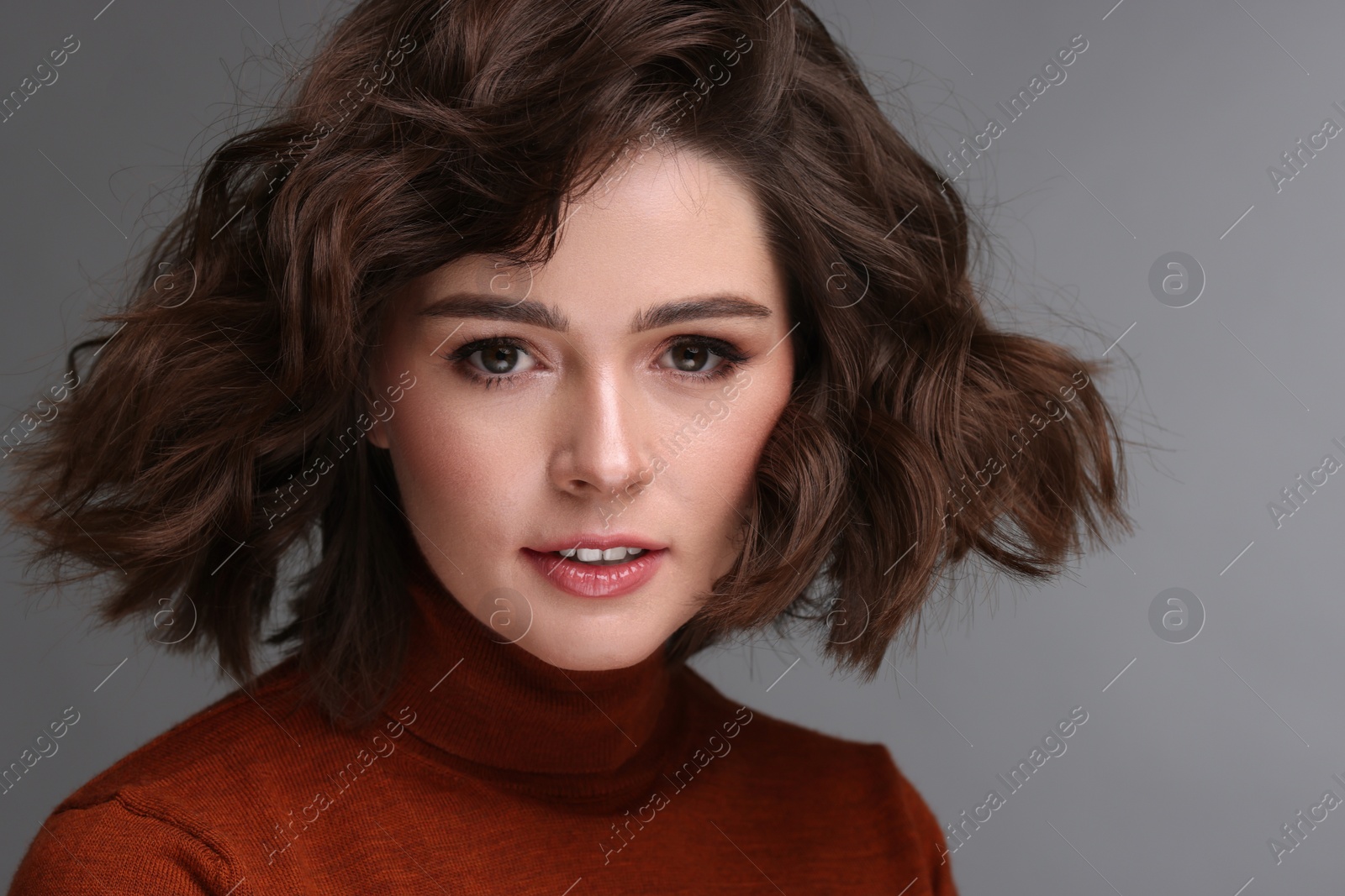 Photo of Portrait of beautiful young woman with wavy hairstyle on grey background