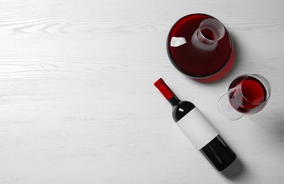 Decanter, glass and bottle with red wine on wooden background, top view