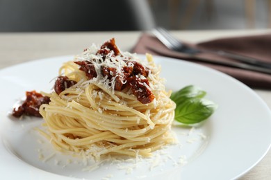 Photo of Tasty spaghetti with sun-dried tomatoes and parmesan cheese on table, closeup. Exquisite presentation of pasta dish