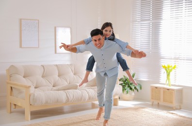 Photo of Father and daughter having fun near sofa in living room