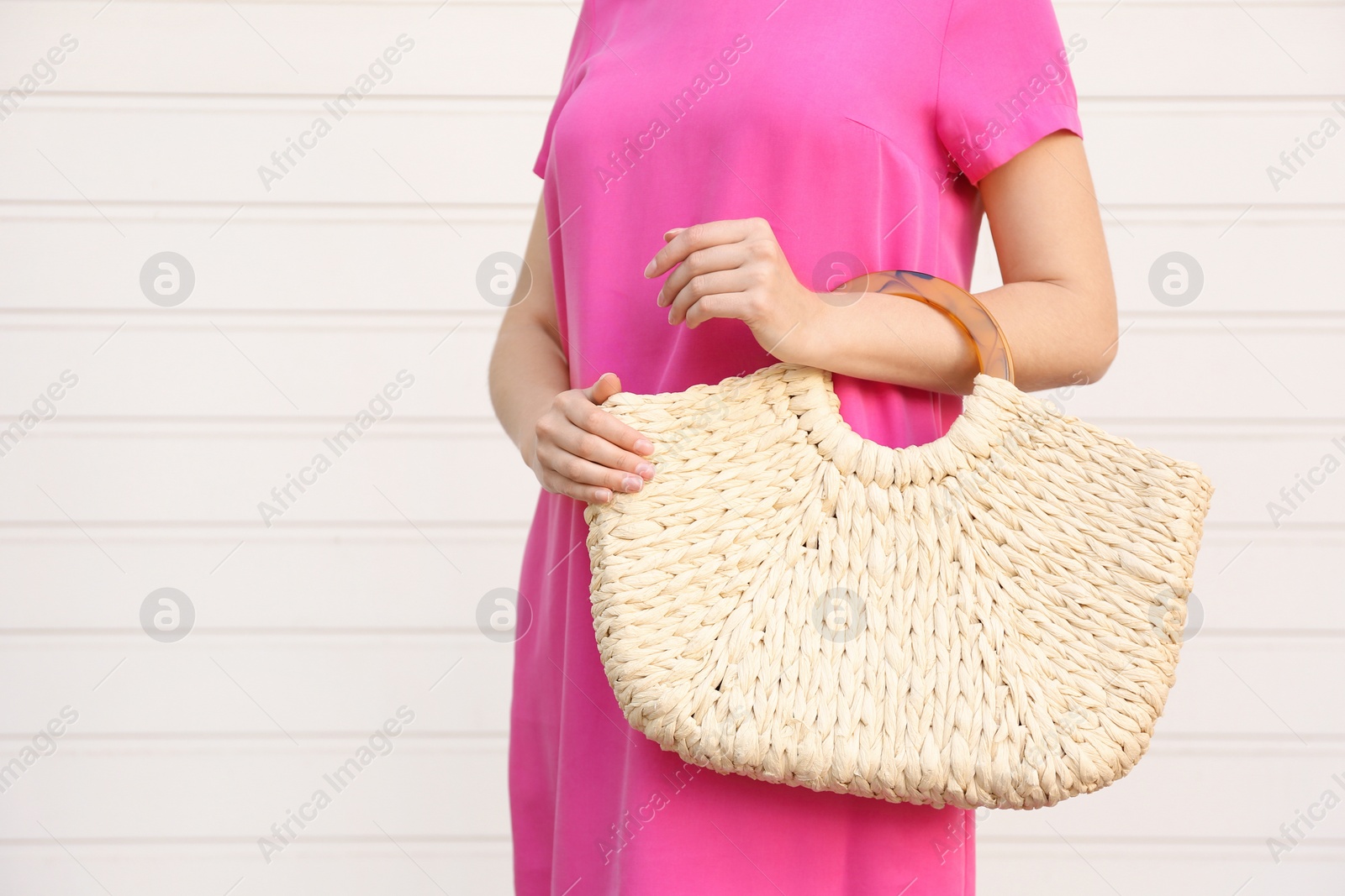 Photo of Young woman with stylish straw bag near white wall, closeup