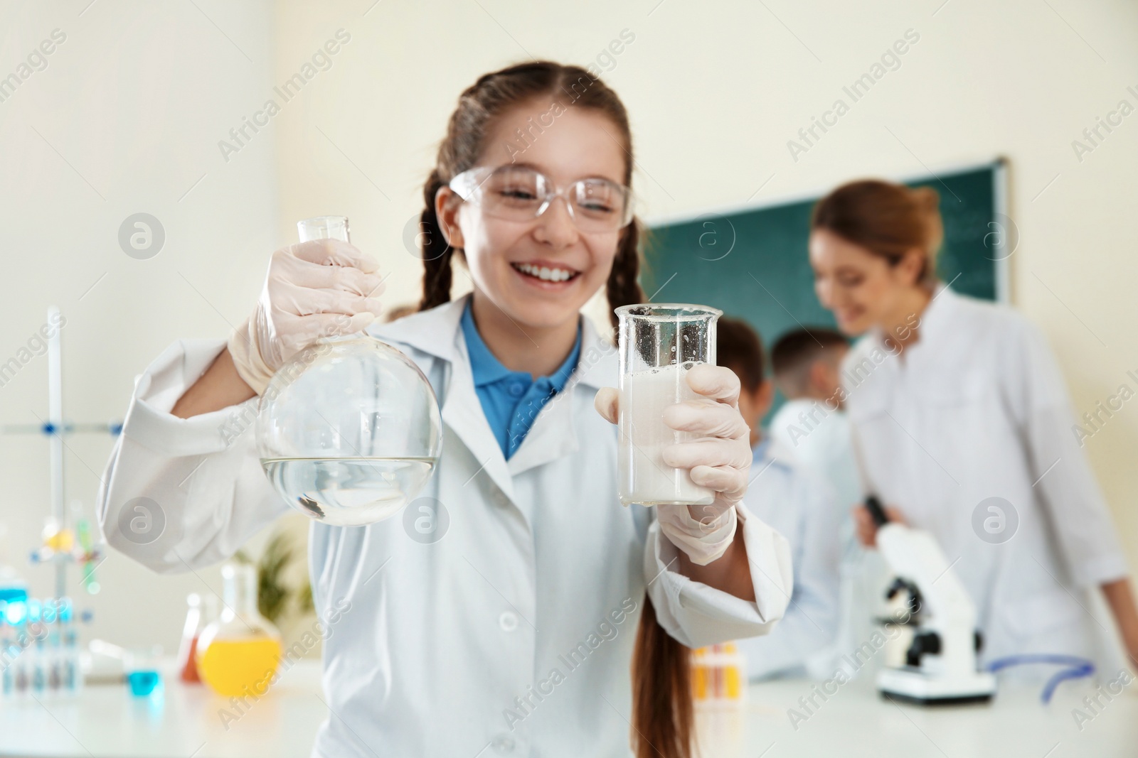 Photo of Schoolgirl making experiment in chemistry class, closeup
