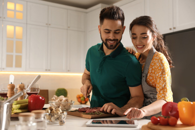 Lovely young couple with tablet cooking together in kitchen