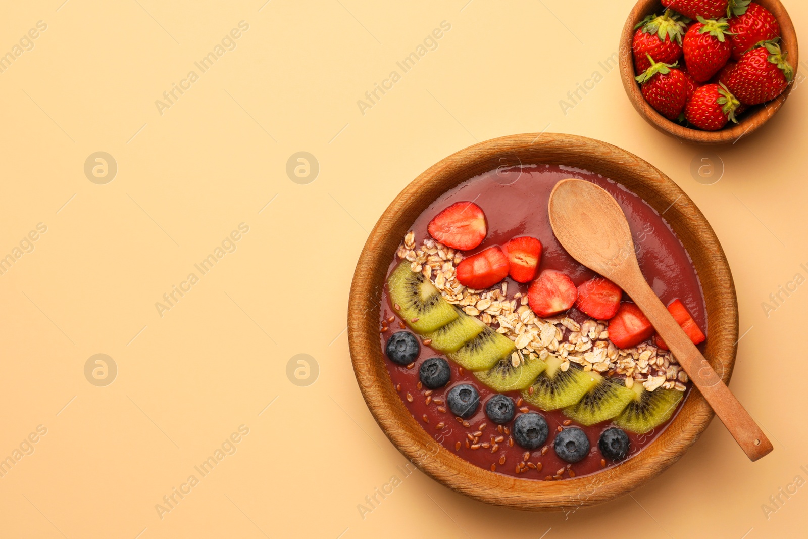 Photo of Bowl of delicious smoothie with fresh blueberries, strawberries, kiwi slices and oatmeal on color background, flat lay. Space for text