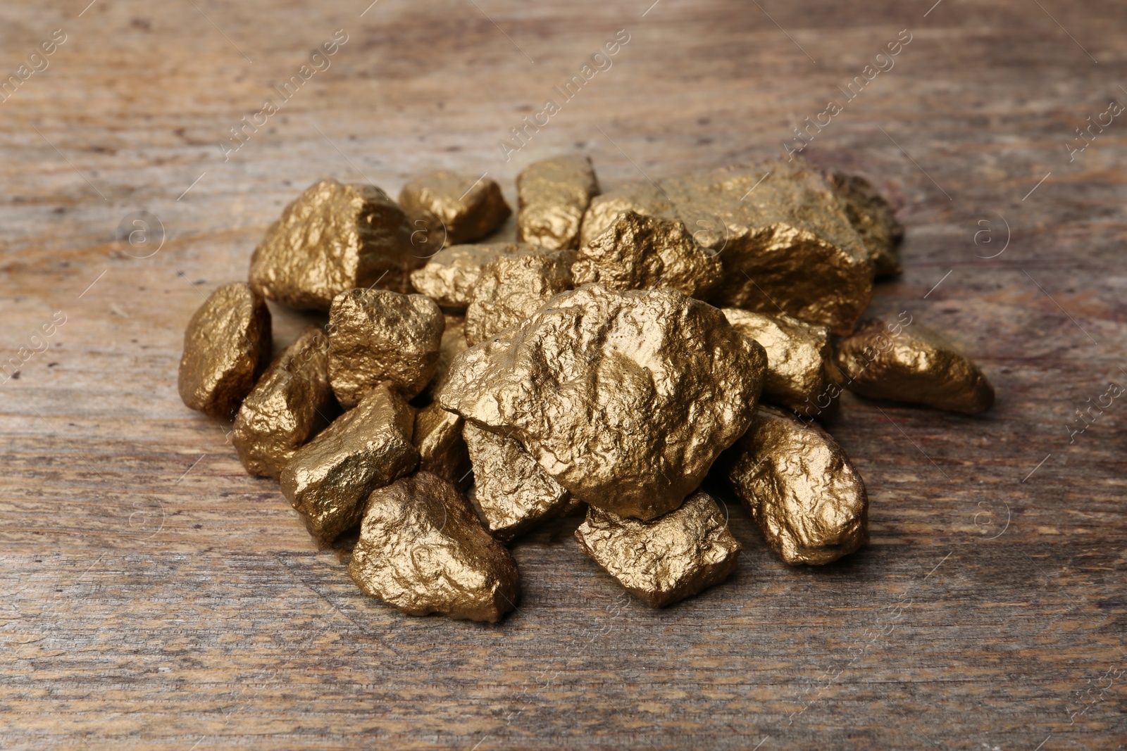 Photo of Pile of gold nuggets on wooden background