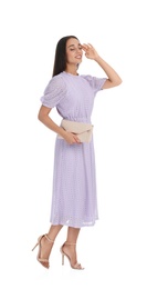Young woman wearing stylish lilac dress with elegant clutch on white background