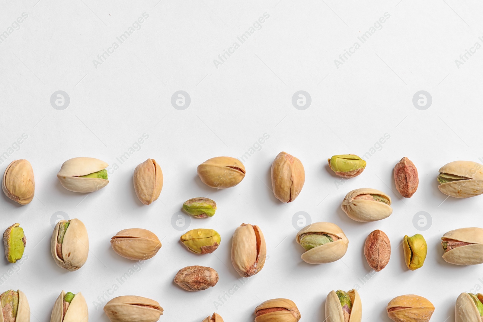 Photo of Composition with organic pistachio nuts on white background, top view. Space for text