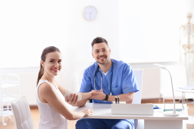 Photo of Male orthopedist applying bandage onto patient's elbow in clinic