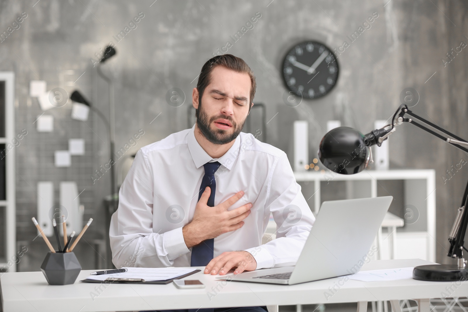 Photo of Young man suffering from chest pain in office