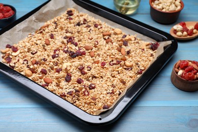 Photo of Tray with tasty granola, nuts and dry fruits on blue wooden table