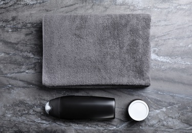 Towel, shower gel and cream on grey marble background, flat lay. Men's cosmetics
