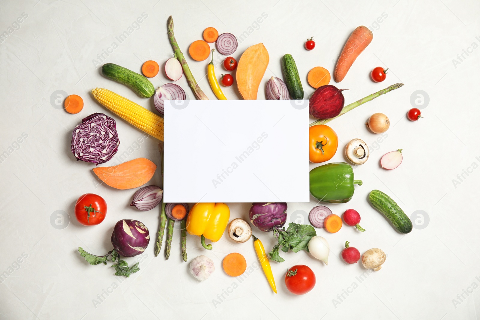 Photo of Flat lay composition with fresh vegetables and blank card for text on light background