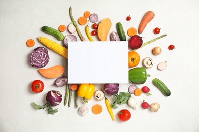 Flat lay composition with fresh vegetables and blank card for text on light background