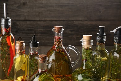 Photo of Cooking oil with different spices and herbs in bottles on wooden background