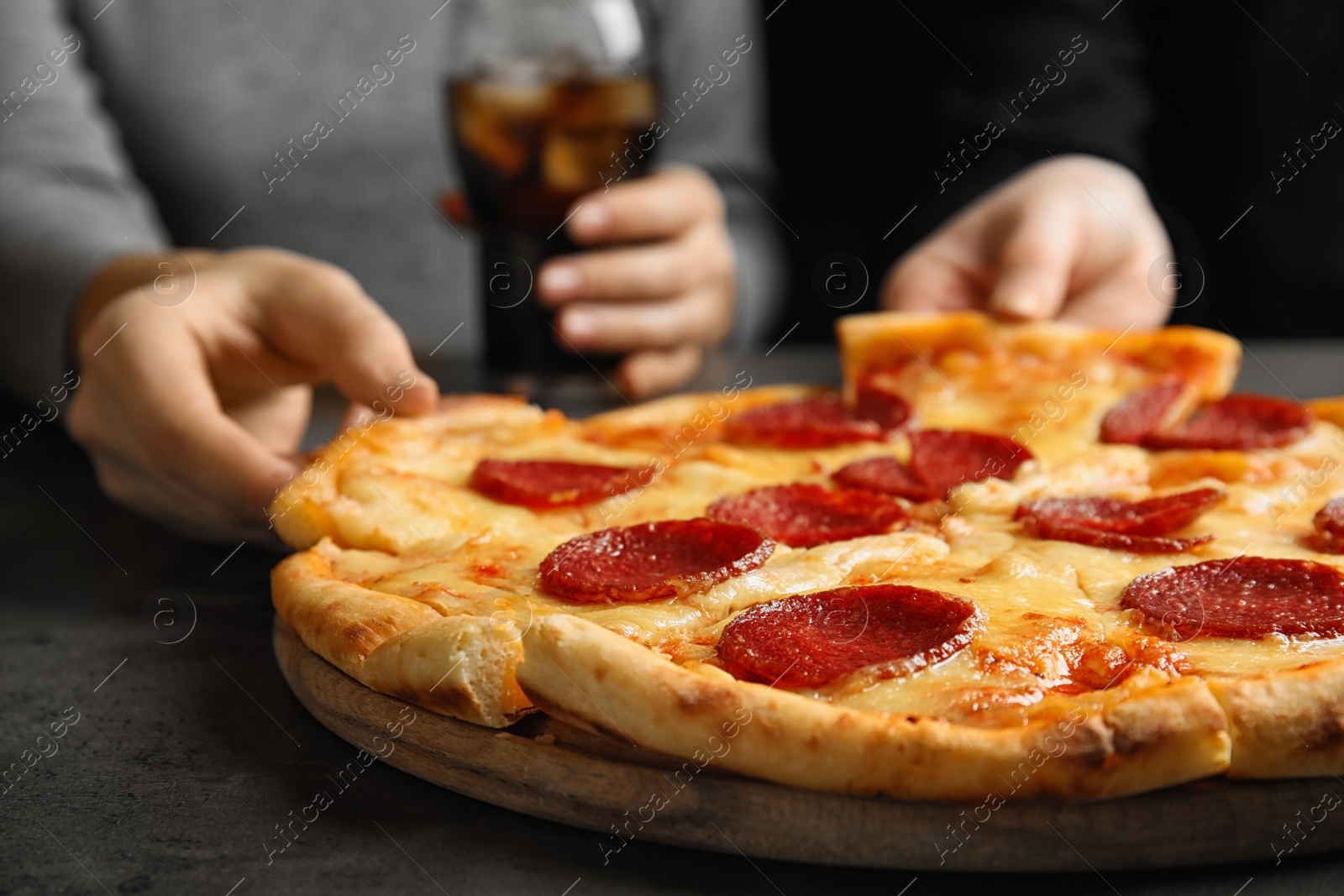 Photo of Women taking tasty pepperoni pizza at grey table, closeup