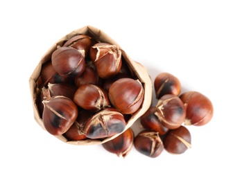Photo of Paper bag with tasty roasted edible chestnuts on white background, top view