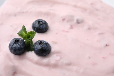 Tasty yogurt, mint and blueberries as background, closeup. Space for text