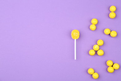 Photo of Different lemon candies on purple background, top view. Space for text