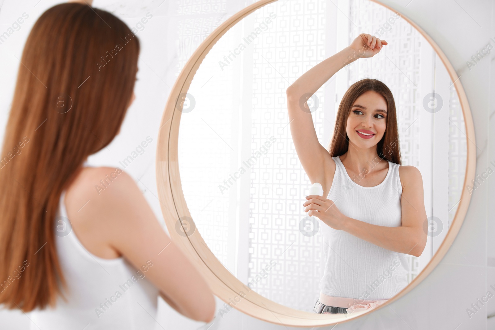 Photo of Beautiful young woman applying deodorant in bathroom