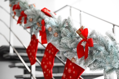 Photo of Santa stockings and garland on railing indoors. Christmas decor idea