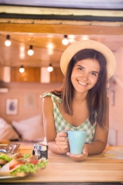 Photo of Young woman with cup in trailer, view from outside. Camping vacation