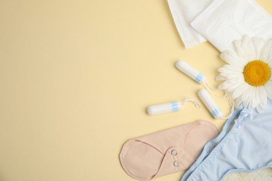 Photo of Tampons and other menstrual hygienic products on yellow background, flat lay. Space for text