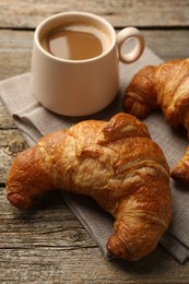 Photo of Delicious fresh croissants and cup of coffee on table, closeup