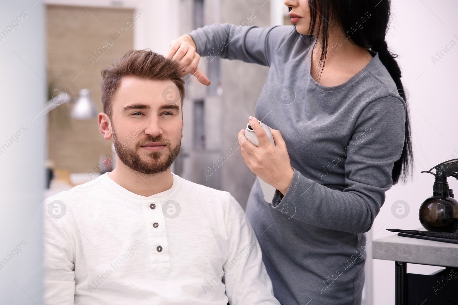 Photo of Professional female hairdresser working with client in salon