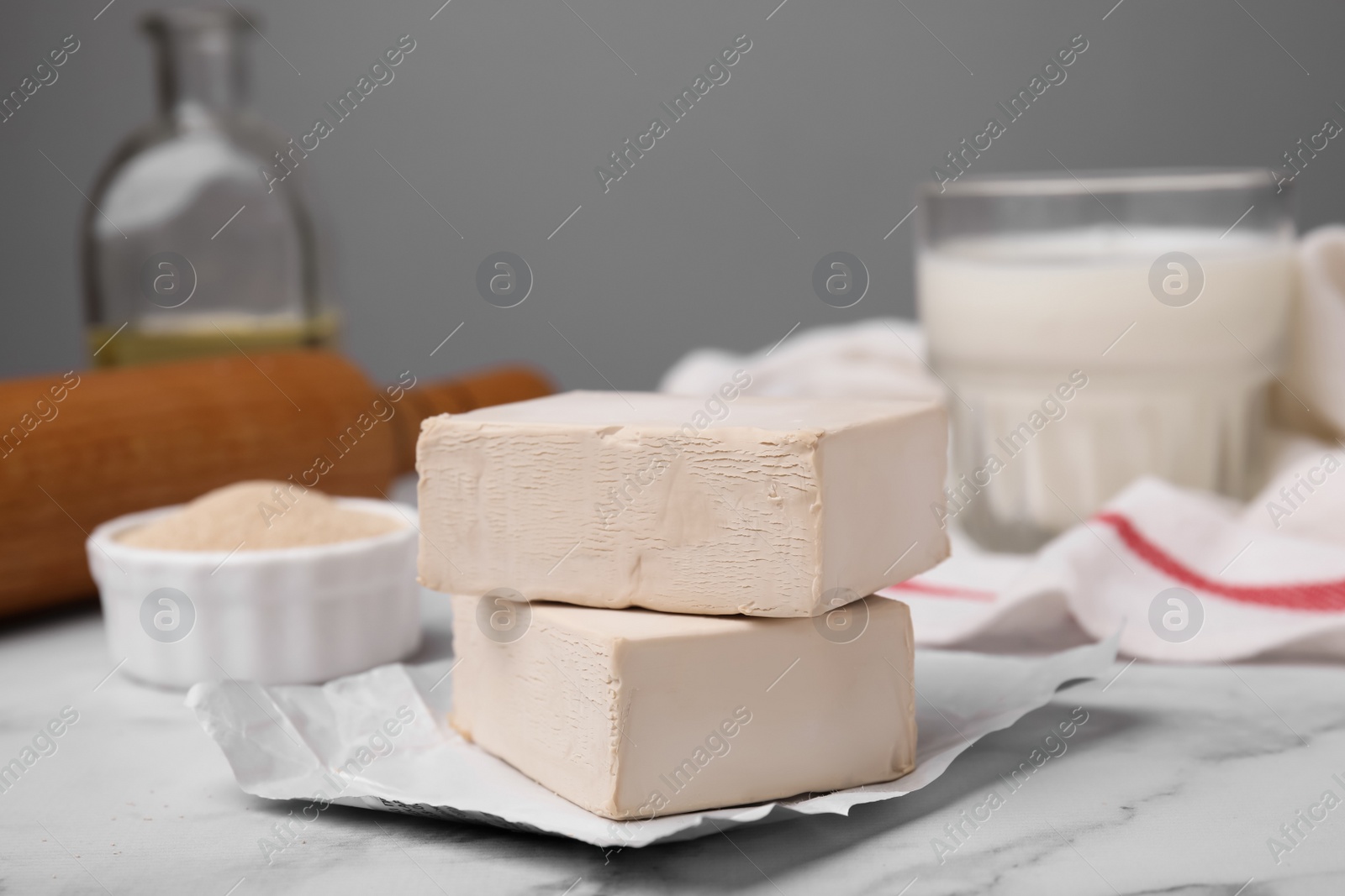 Photo of Granulated and compressed yeast on white marble table, closeup