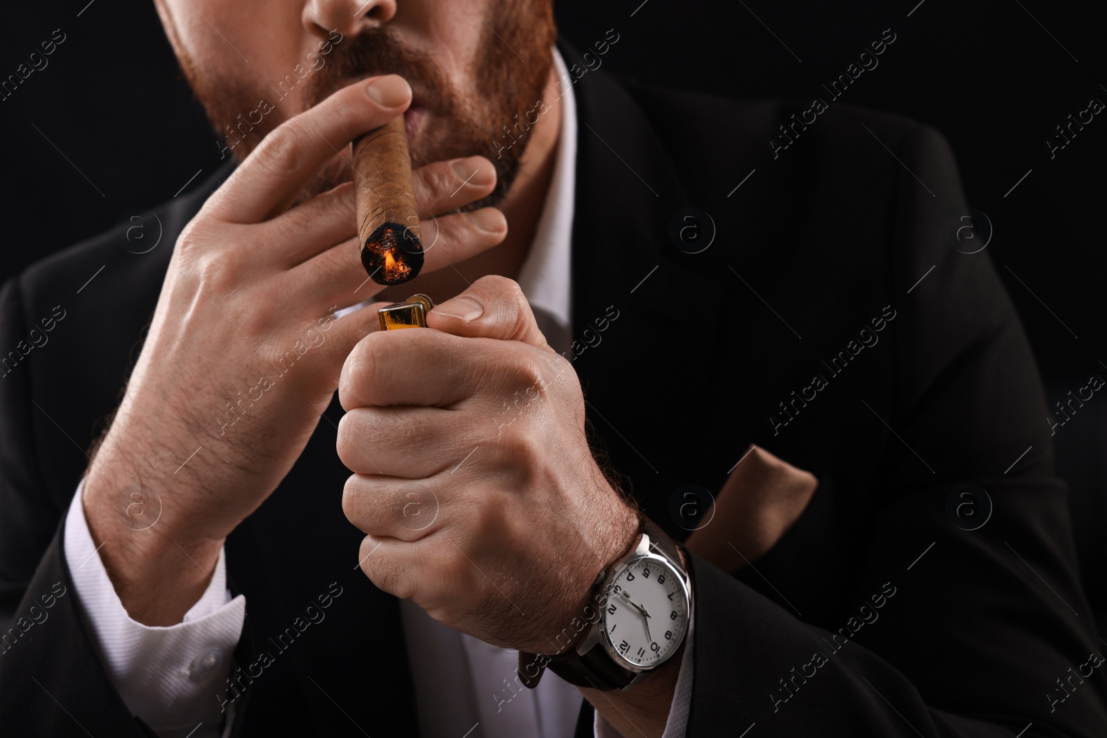 Photo of Man lightning cigar on black background, closeup