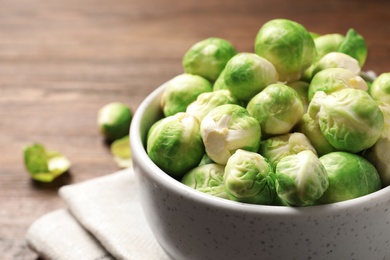 Photo of Bowl of fresh Brussels sprouts on table, closeup. Space for text