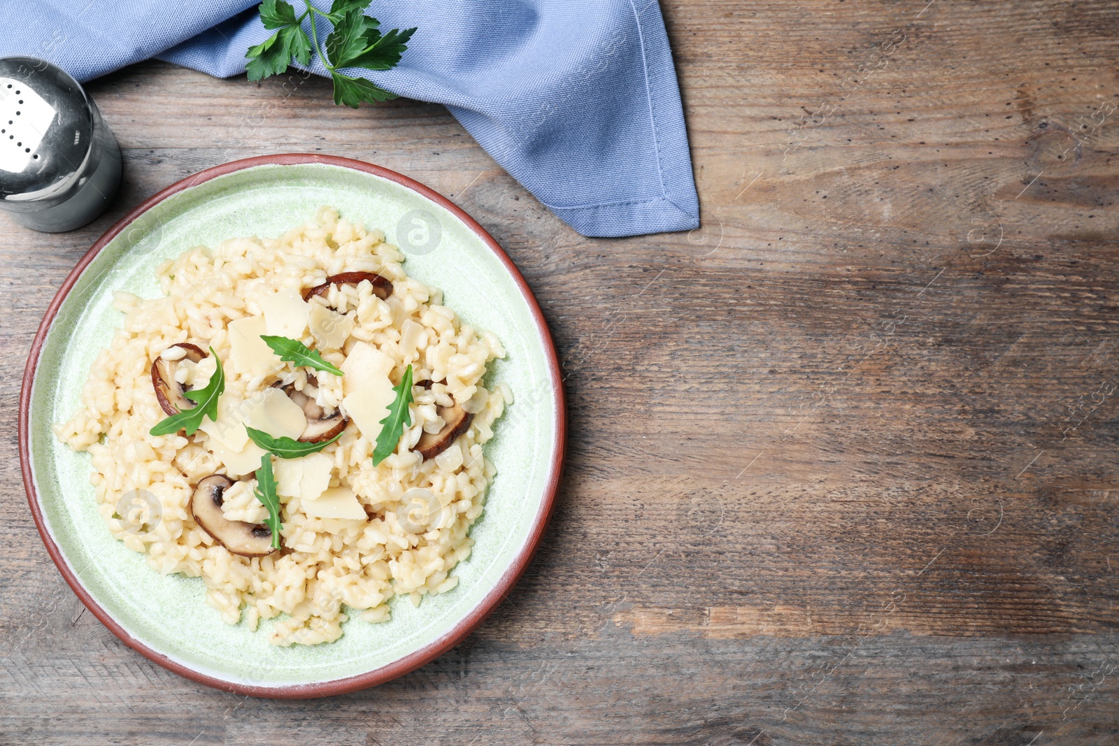 Photo of Delicious risotto with cheese and mushrooms on wooden table, flat lay. Space for text