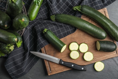 Green ripe zucchinis and wooden board on black slate table, flat lay