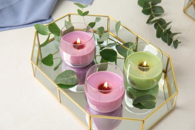 Photo of Tray with burning candles and eucalyptus on light table