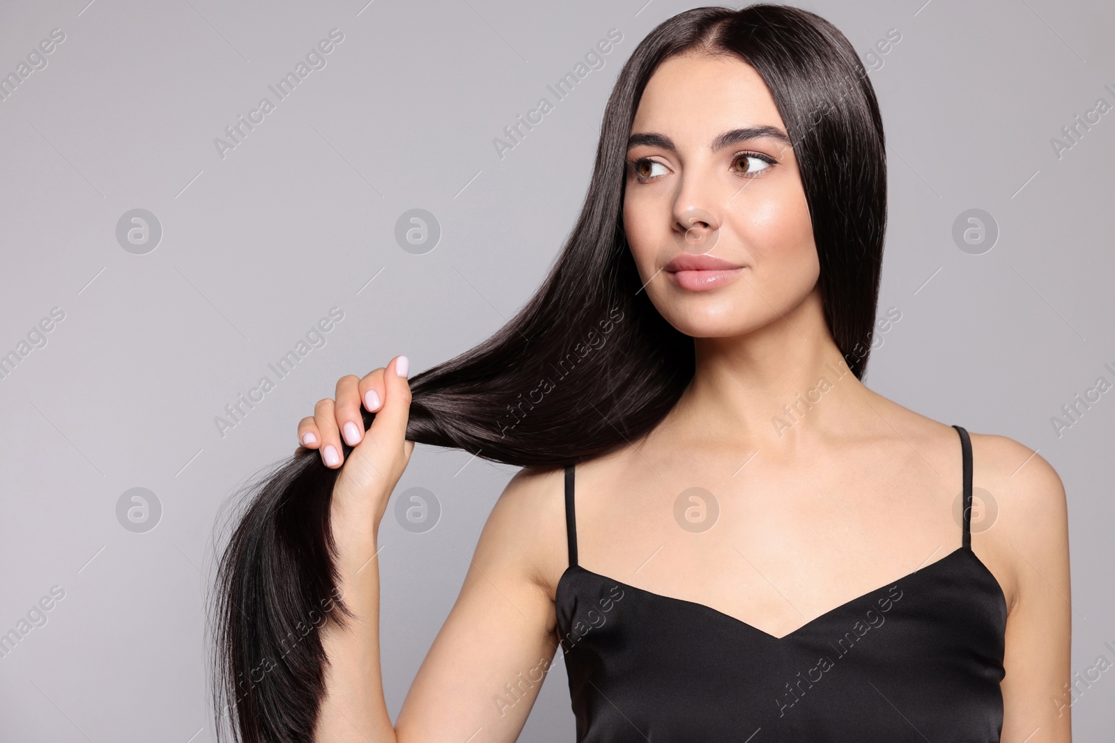 Photo of Portrait of beautiful young woman with healthy strong hair on light grey background. Space for text