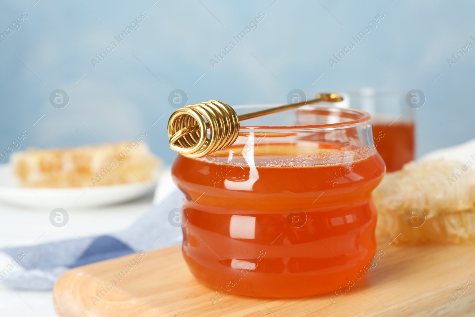 Photo of Glass jar with sweet honey and dipper on table, closeup